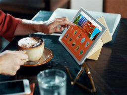 Tableta táctil de mano que muestra la pantalla de aprendizaje de idiomas con la otra mano sosteniendo café