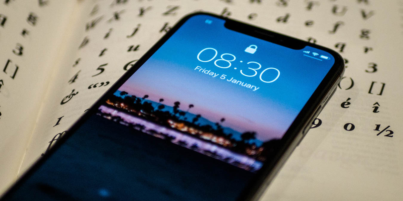 Photo of an iPhone X's lock screen with a background of a book page